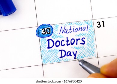 Woman Fingers With Pen Writing Reminder National Doctors Day In Calendar. March 30. 