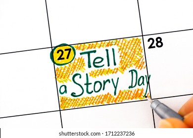 Woman Fingers With Pen Writing Reminder Tell A Story Day In Calendar. April 27. 