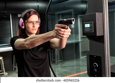 A Woman Firing A Hand Gun At An Indoor Gun Range.