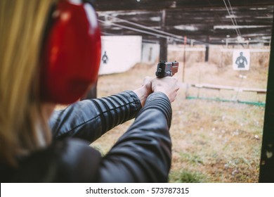 Woman firing with pistol on target at the shooting range. Close-up.