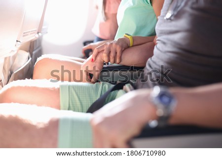 Woman firmly holds man's hand during flight in plane. Aerophobia of altitude concept.