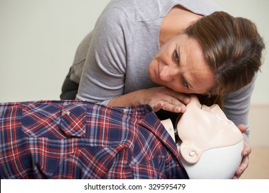 Woman In First Aid Class Checking Airway On CPR Dummy
