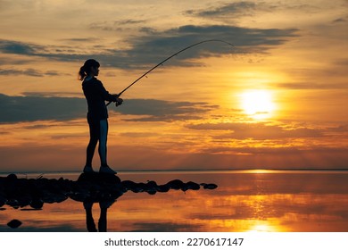 Woman fishing on Fishing rod spinning at sunset background.