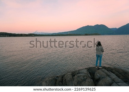 a woman fishing at the Panguipulli lake with the volcano behind with a beautiful sunset.