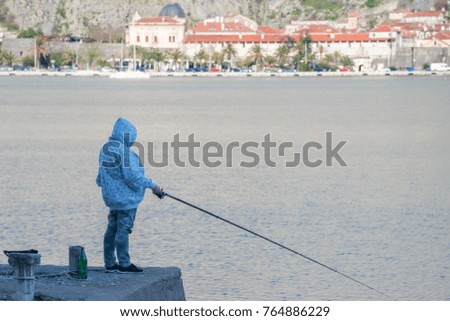 Woman is fishing with a fishing rod from a pier