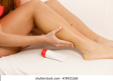 Woman fit fitness girl putting ointment cream on injured calf. Health care crapm problem muscle pain in leg