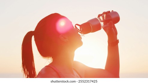 Woman, fitness and drinking water with beach sunset for hydration, mineral liquid or refreshment. Active, female person or runner with lens flare, aqua beverage or thirst for natural sustainability - Powered by Shutterstock