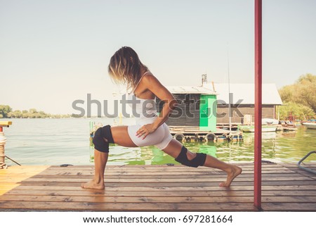 woman fitness instructor exercise outdoor on wooden river raft summer day