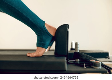 Woman fitness trainer demonstrates Pilates exercises on simulator active athletic routine - Powered by Shutterstock