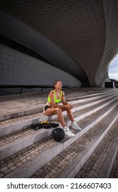 Woman in fitness wear have a rest after workout with a heavy medicine ball and trx straps outdoors.. Sporty girl with fit body in sportswear posing on the stairs.