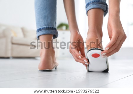 Woman fitting orthopedic insole at home, closeup
