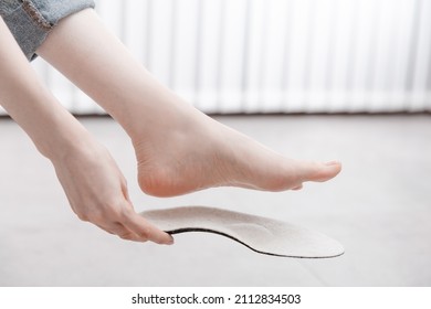 Woman Fitting Orthopedic Insole Indoors, Close Up. Girl Holding An Insole Next To Foot At Home. Orthopedic Insoles. Foot Care Banner. Flat Feet Correction. Treatment And Prevention Of Foot Diseases.