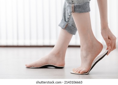 Woman fitting orthopedic insole indoors, close up. Girl holding an insole next to foot at home. Orthopedic insoles. Foot care banner. Flat Feet Correction. Treatment and prevention of foot diseases. - Shutterstock ID 2143106663