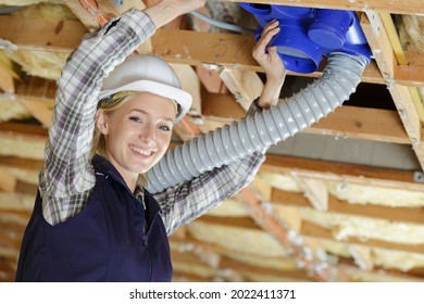 Woman Fitting Ventilation Hose Into Roof Space