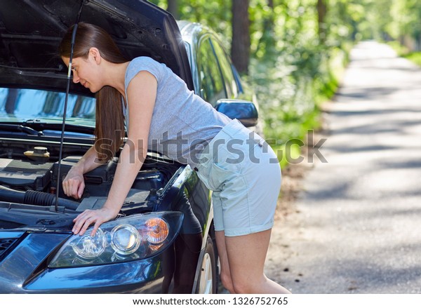 Woman fixing car on\
road. Outdoor portrait.