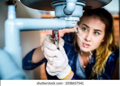 Woman fixing kitchen sink - Shutterstock ID 1038657541