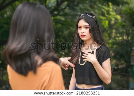 A woman is flabbergasted by her friend criticizing her. A stressful encounter outside. Stock foto © 