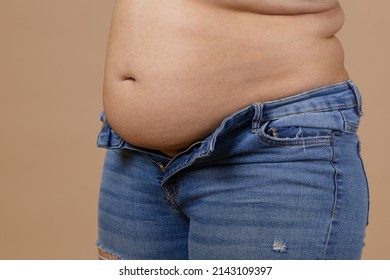 Woman with flabby belly and thick sides showing waist in unzipped jeans of blue color. Sudden weight gain. Visceral fat. Body positive. Tight little clothes. Need for wardrobe change.
