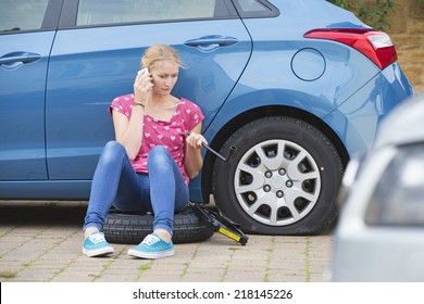 Woman With Flat Tire On Car Phoning For Assistance