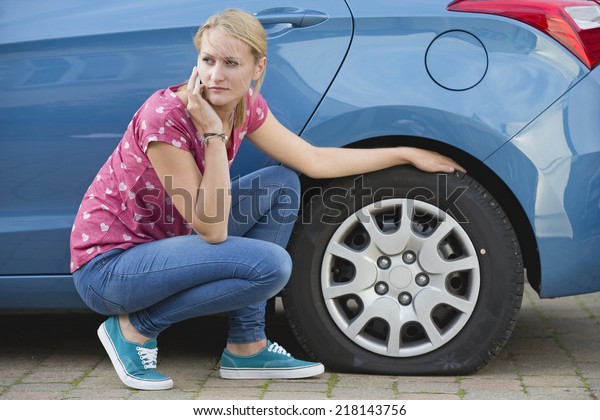 Woman With
Flat tire On Car Phoning For
Assistance