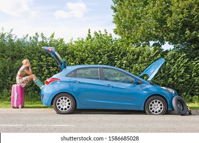 Woman With Flat Tyre On Car Resting Feet On Suitcase