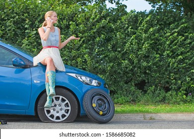 Woman With Flat Tyre On Car Phoning For Assistance