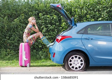 Woman With Flat Tyre On Car Phoning For Assistance