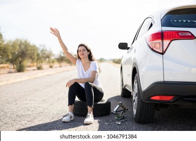 Woman With Flat Tyre On Her Car Hailing Oncoming Traffic On Country Road For Help