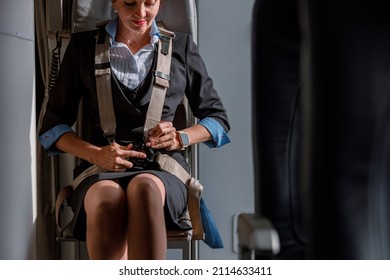 Woman Flight Attendant Fastening Seatbelt In Airplane