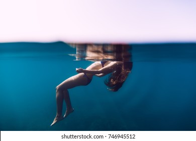 Woman floating in ocean, girl is relaxing. Underwater photo
