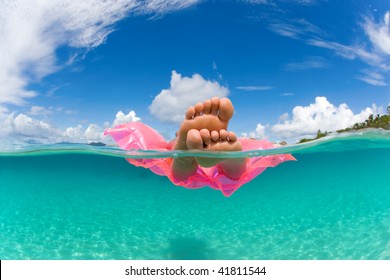 woman floating on inflatable raft relaxing and sunbathing in tropical water with feet showing under over