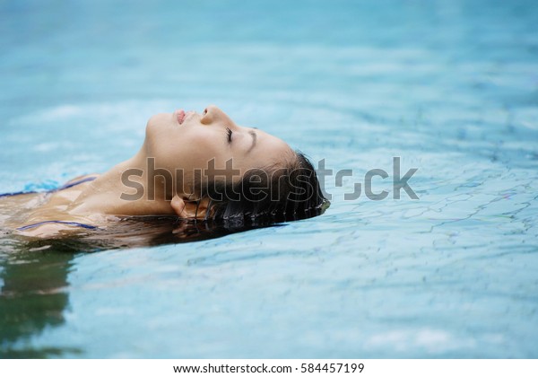 Woman floating in swimming\
pool