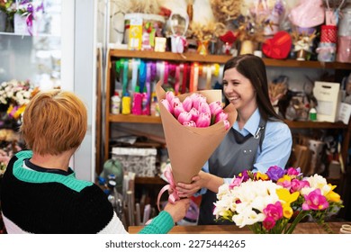 Woman florist gives a bouquet to the buyer. Bouquet of pink tulips in craft. Flower shop, small business, personality, mothers day, birthday, women's day, valentines day. Thanks for visiting us  - Powered by Shutterstock