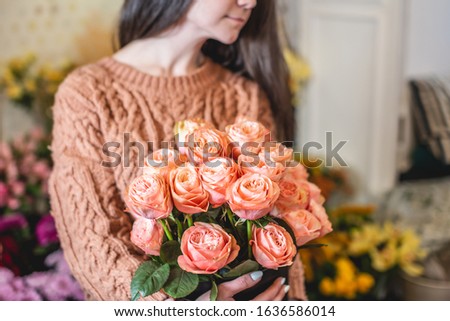 Woman florist holds a large beautiful bouquet of blooming pink roses in a flower shop