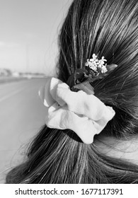 A Woman With A Flower In Her Low Ponytail Looking Down The Road — Black And White