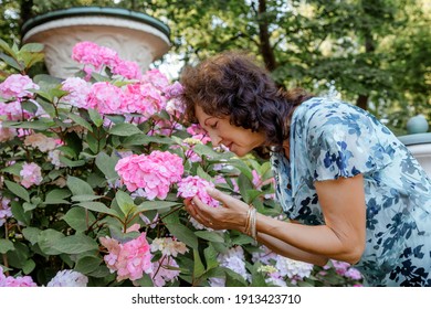 Woman With A Flower. Senior Hispanic Woman Working In Garden. Close-up Portrait Of An Older Woman On Walk With Flowers. Park.