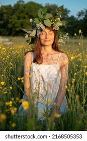 Woman with a flower wreath on her head sits in a field and enjoys the sun. - Shutterstock ID 2168505353