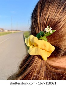 A Woman With Flowers In Her Low Ponytail Looking Down The Road