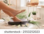 Woman with flowers undergoing spa pedicure treatment on couch in spa salon