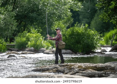 Woman fly fishing on the river in Finland - Powered by Shutterstock