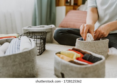 Woman folding clothes, organizing stuff in boxes and baskets. Concept of minimalism lifestyle and japanese t-shirt folding system. Minimalist storage and arrangement in wardrobe