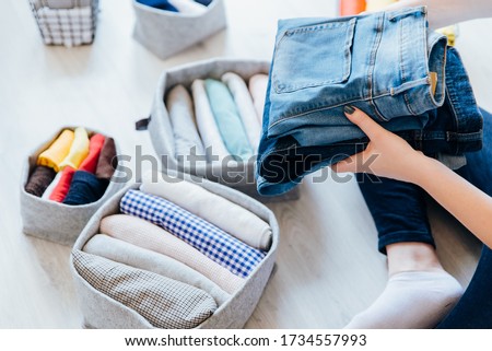Woman folding clothes, organizing stuff in baskets and boxes. Concept of clothes storage, minimalism lifestyle and japanese t-shirt folding system. Tidy up in wardrobe ストックフォト © 
