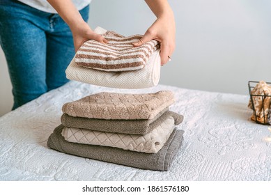 Woman Folding Clothes And Towels In Bedroom, Organizing Laundry In Boxes And Baskets. Concept Of Minimalist Lifestyle And Japanese Konmari Folding System. Tidy Up Wardrobe