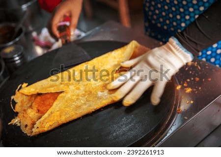 Woman folding and making savoury egg pancake in a small local street outlet bakery in Yichang town, China