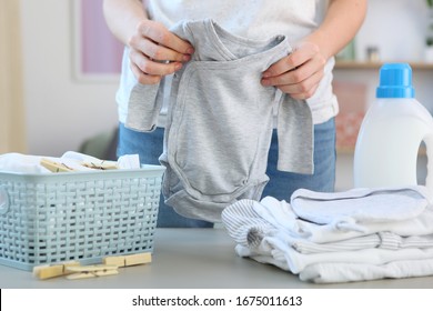 A Woman Folds Clean And Fresh Baby Clothes. Washing Baby Clothes.
