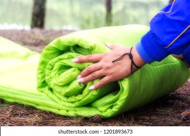 A woman folds and packs a sleeping bag, going on a journey through the forest. The concept of tourism and ecotourism. Equipment for traveling.