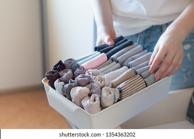 The woman folds t-shirts in the drawer. A woman is tidying up the closet. Vertical storage of clothing.