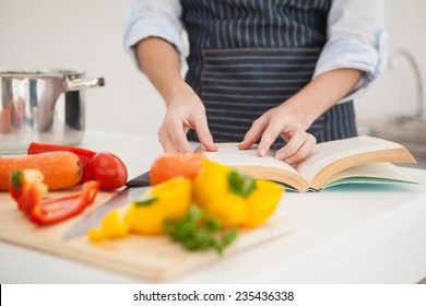 Woman following a recipe in book at home in the kitchen - Powered by Shutterstock