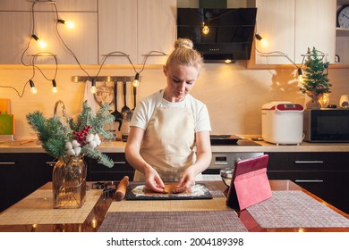 Woman Following Recipe On Digital Tablet And Cooking Christmas Gingerbread Cookies On Her Kitchen.