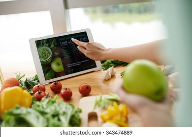 Woman following recipe on website to make healthy smoothie - Powered by Shutterstock